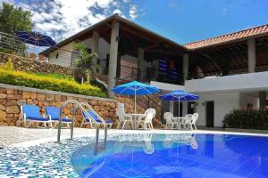 una piscina con sillas y sombrillas junto a una casa en Hotel Sierra de la Cruz, en Valle de San José