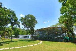 un grand bâtiment en verre dans un parc arboré dans l'établissement White Feather Resort Kauncha, à Silvassa