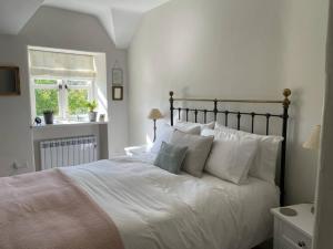 a bedroom with a bed with white sheets and pillows at Lovely 2-Bed Cottage in Blaenau Ffestiniog in Blaenau-Ffestiniog