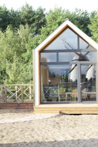 a small house with a large window in the dirt at Apartamenti Vējdzirnavas in Ventspils