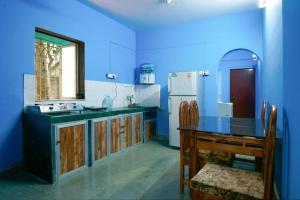 a blue kitchen with a table and a refrigerator at Satya Vacation Stay in Alibaug