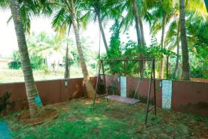 a swing set in a yard with palm trees at Satya Vacation Stay in Alibaug