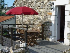- une table en bois avec un parasol rouge sur le balcon dans l'établissement Aux Pierres de Nozières, à Gramat