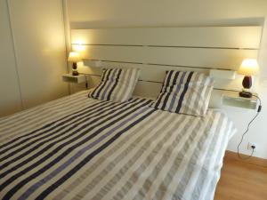 a bedroom with a bed with striped sheets and two lamps at Aux Pierres de Nozières in Gramat