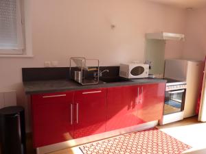 a kitchen with red cabinets and a microwave at Aux Pierres de Nozières in Gramat