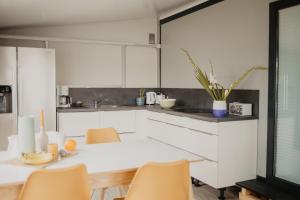 a kitchen with white cabinets and a table and chairs at Camping Strukkamphuk in Strukkamp auf Fehmarn
