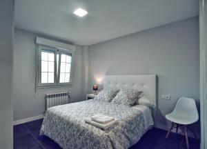 um quarto com uma cama, uma cadeira e uma janela em Apartamento Las Perdices em Pontevedra