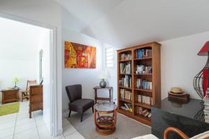 a living room with a chair and a book shelf at La Villa Bel Océan - Saint Gilles Bains in Saint-Gilles les Bains