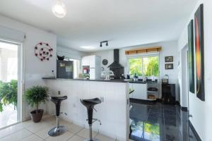 a kitchen with a counter and stools in it at La Villa Bel Océan - Saint Gilles Bains in Saint-Gilles les Bains