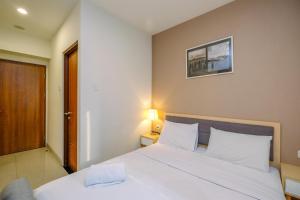 a bedroom with a large white bed and a lamp at Modern and Spacious Studio with City View @ Grand Kamala Lagoon Apartment By Travelio in Pekayon Satu +18 photos