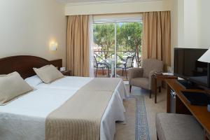 a hotel room with a bed and a television at Hipotels Barrosa Garden in Chiclana de la Frontera
