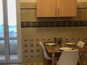 a dining room table with white chairs and a kitchen at Casella - Appartement centre ville tout équipé in Bastia