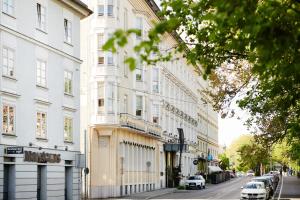 a street with white buildings and cars parked on the street at Grand Hôtel Wiesler - Centre of Graz in Graz