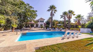 ein Swimmingpool mit Stühlen und ein Haus in der Unterkunft Casa Rural Santa Ana in Marchena