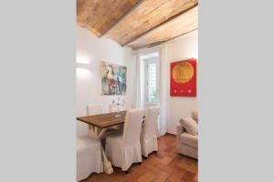 a dining room with a wooden table and white chairs at Idyllia - lovely Colosseum loft apartment in Rome