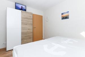 a bedroom with a white bed and a wooden door at Ferienwohnung im Haus Hafenlicht in Neuharlingersiel