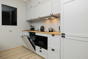 a kitchen with white cabinets and a black oven at Nadmorskie Studio z Balkonem - Grunwaldzka Pobierowo by Renters in Pobierowo