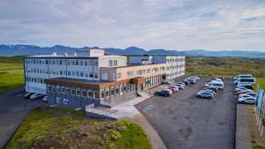 a large building with cars parked in a parking lot at Fosshotel Stykkisholmur in Stykkishólmur