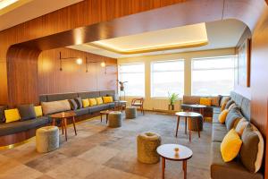 a lobby with couches and tables and windows at Fosshotel Stykkisholmur in Stykkishólmur