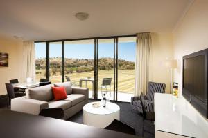 a living room with a couch and a large window at Rydges Mount Panorama Bathurst in Bathurst