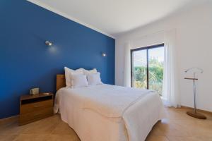 a blue bedroom with a bed and a window at Villa Paraiso by Garvetur in São Bartolomeu de Messines +13 photos