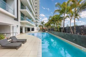 a swimming pool next to a building with palm trees at Wyndham Resort Surfers Paradise in Gold Coast