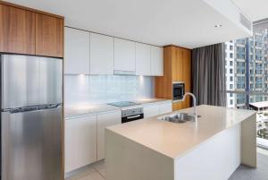 a kitchen with white cabinets and a stainless steel refrigerator at Wyndham Resort Surfers Paradise in Gold Coast
