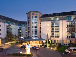 un hôtel avec des voitures garées dans un parking dans l'établissement Novotel Mainz, à Mayence