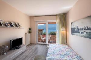 a living room with a television and a balcony at Lake view with Aircon - 5 minutes from the beach! in Brenzone sul Garda