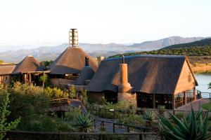 ein großes Haus mit einem Strohdach in der Unterkunft Buffelsdrift Game Lodge in Oudtshoorn