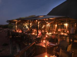 a restaurant with people sitting at tables at night at Buffelsdrift Game Lodge in Oudtshoorn