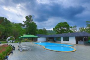 a swimming pool with a patio and a building at White Feather Resort Kauncha in Silvassa