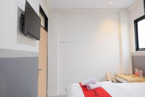 een kamer met een bed en een tv aan de muur bij RedDoorz Plus near Taman Anggrek Mall in Jakarta