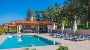 a swimming pool with chairs and a gazebo at Vitis Apartment Istra in Tinjan