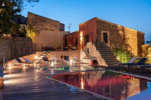 a swimming pool with chairs and a building at Gratteri Resort in Gratteri