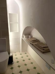 a bathroom with a toilet and a shelf with towels at Casa do Menino Jesus in Évora