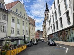 a city street with parked cars and a clock tower at City by BestChoice - FREE Parking - Self Check-in in Graz