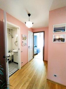 um quarto com paredes cor-de-rosa e uma casa de banho com uma cama em SUNSET Apartment Near Sea - family friendly space with bath and good coffee em Ventspils