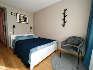 a bedroom with a bed and a chair at SUNSET Apartment Near Sea - Family Friendly space with Bath and Good Coffee in Ventspils