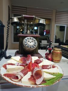 a plate of meat and cheese on a table with a telephone at Guesthouse Eko Piva in Pluzine