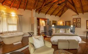 a bedroom with a bed and a bath tub and a tub at Pumba Private Game Reserve in Grahamstown