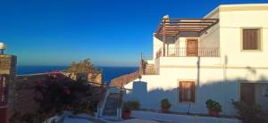 a white house with the ocean in the background at MILTIADIS APARTMENTS in Andros