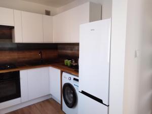 a kitchen with white cabinets and a washing machine at Apartamenty Kletówka in Krosno