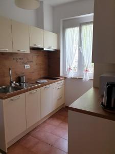 cocina con armarios blancos, fregadero y ventana en Apartments Fink, en Portorož