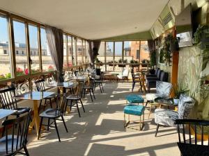 een restaurant met tafels, stoelen en ramen bij Hotel Tritone in Rome