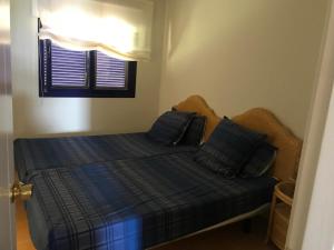 een slaapkamer met een bed met blauwe lakens en een raam bij Meloneras in Meloneras