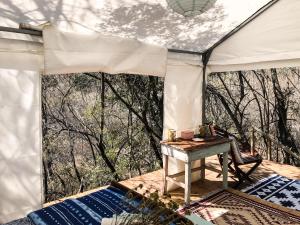 a white tent with a table on a deck at Riverbed Africa in Lydenburg