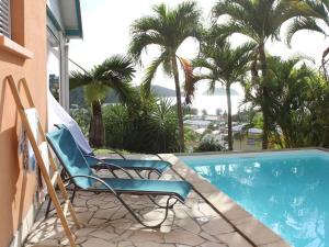 twee stoelen naast een zwembad met palmbomen bij Villa Casalane in Quartiers Anse à lʼÂne