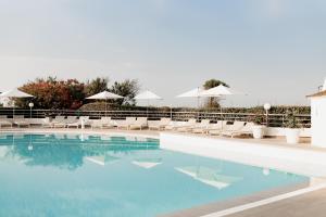 una piscina con sillas y sombrillas blancas en Hôtel Les Corallines – Thalasso & Spa en La Grande-Motte