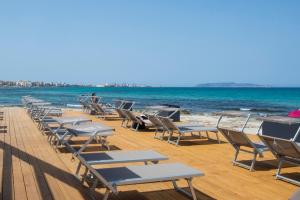 a row of chairs and tables on a beach at Hotel Punta Tipa in Trapani